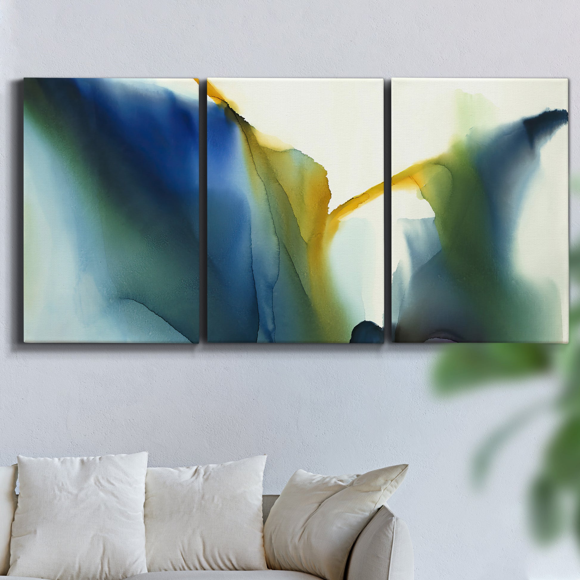 Three-panel canvas wall art featuring soft abstract mask like forms, displayed in a living room above a sofa.