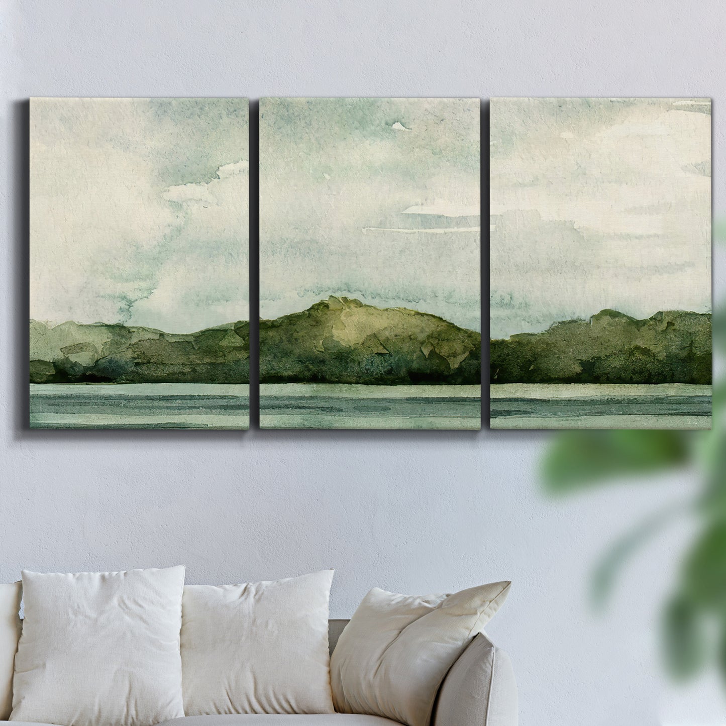 Three-panel canvas wall art featuring riverbank watercolor landscape, displayed in a living room above a sofa.
