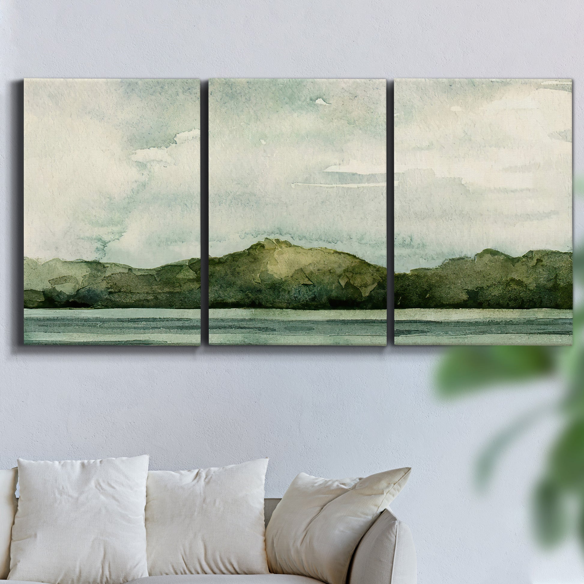Three-panel canvas wall art featuring riverbank watercolor landscape, displayed in a living room above a sofa.
