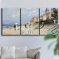 Three-panel canvas wall art featuring figures strolling along beach, displayed in a living room above a sofa.