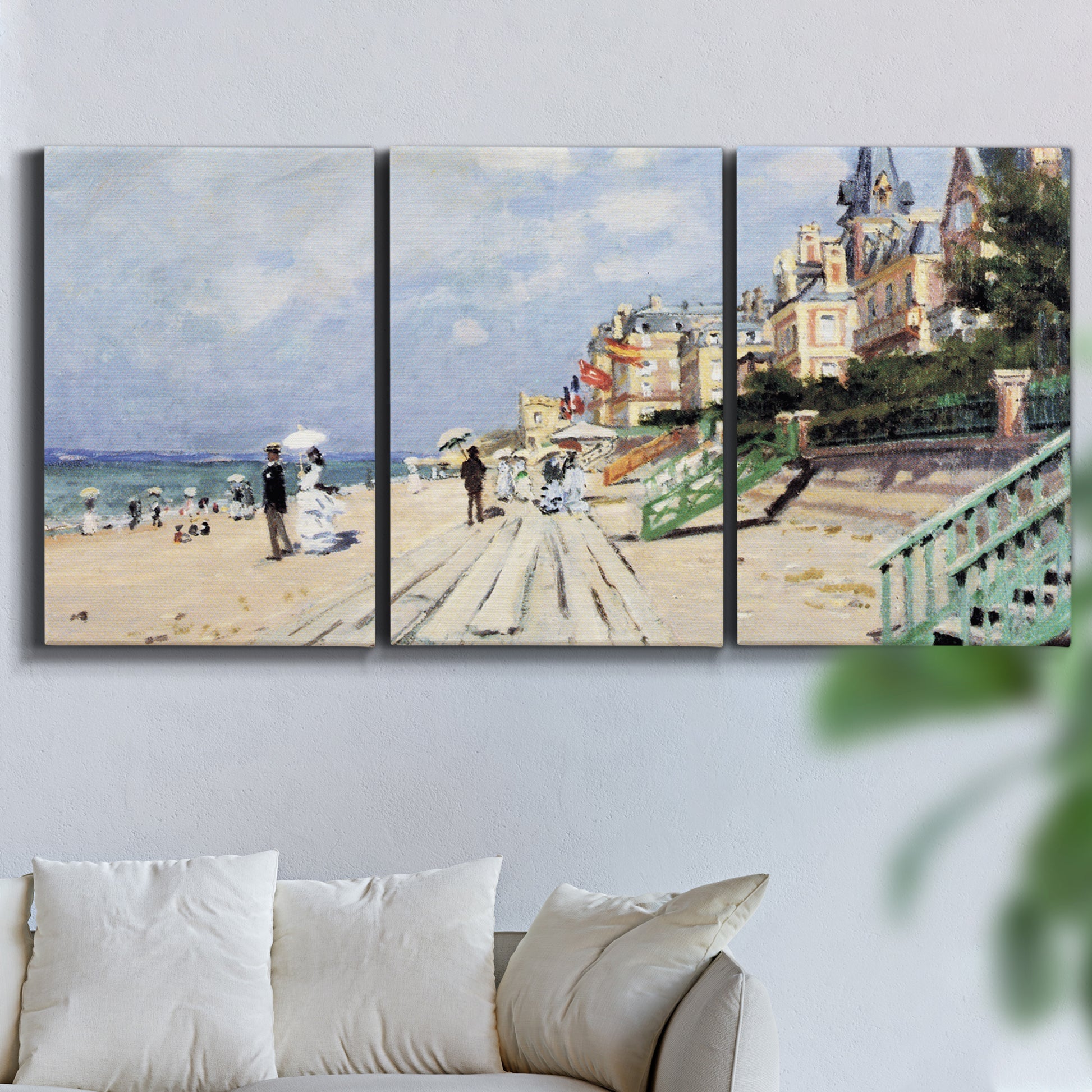 Three-panel canvas wall art featuring figures strolling along beach, displayed in a living room above a sofa.