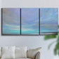 Three-panel canvas wall art featuring coastal shoreline with gentle surf, displayed in a living room above a sofa.