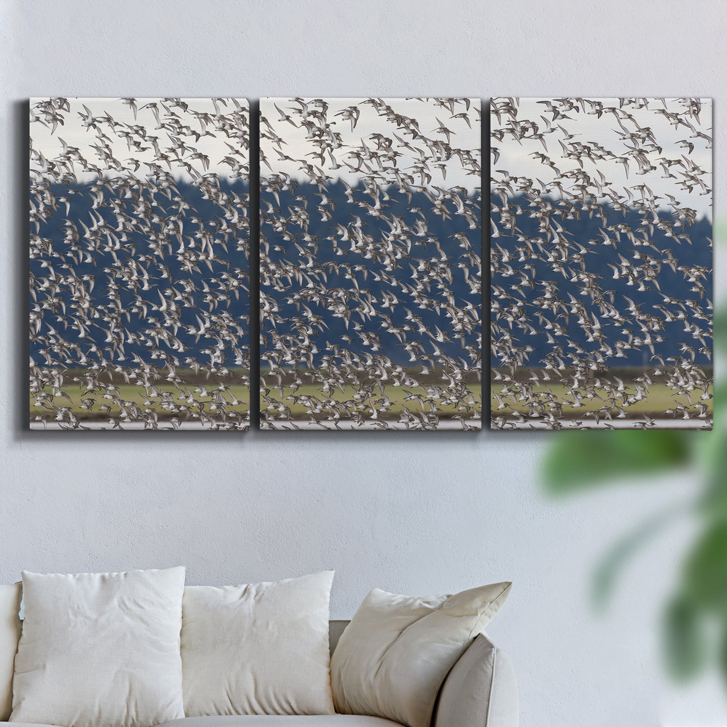 Three-panel canvas wall art featuring group of animals in open field, displayed in a living room above a sofa.