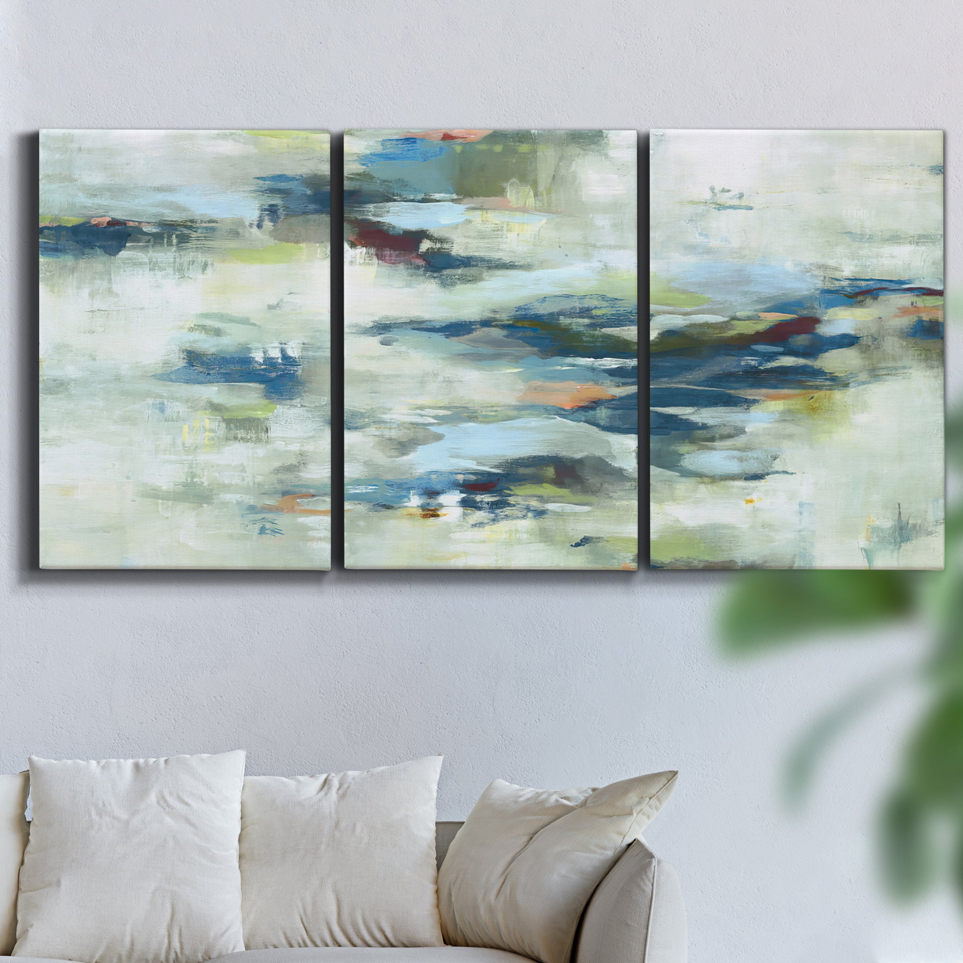 Three-panel canvas wall art featuring dreamlike abstract drifting motion, displayed in a living room above a sofa.