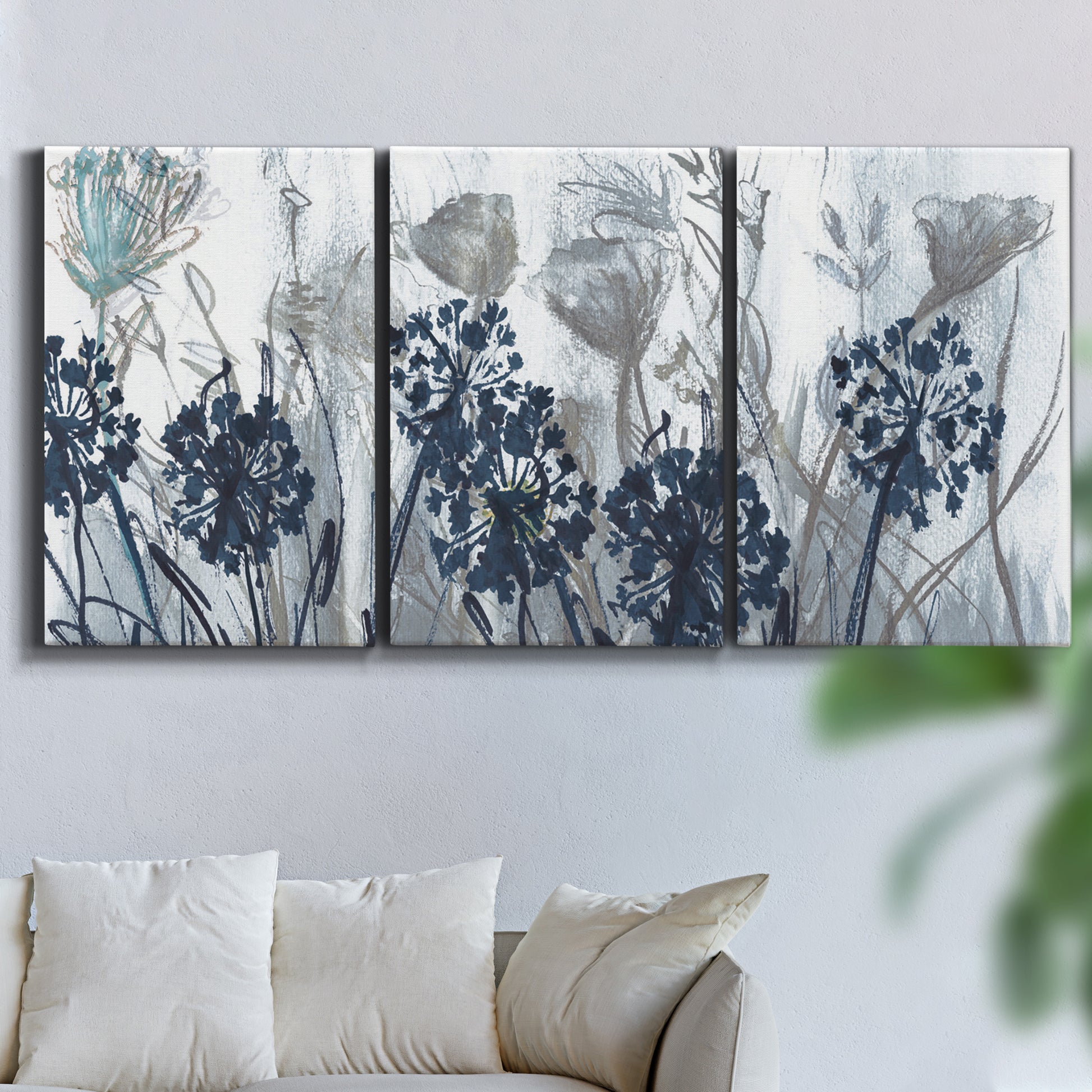 Three-panel canvas wall art featuring indigo floral abstraction, displayed in a living room above a sofa.