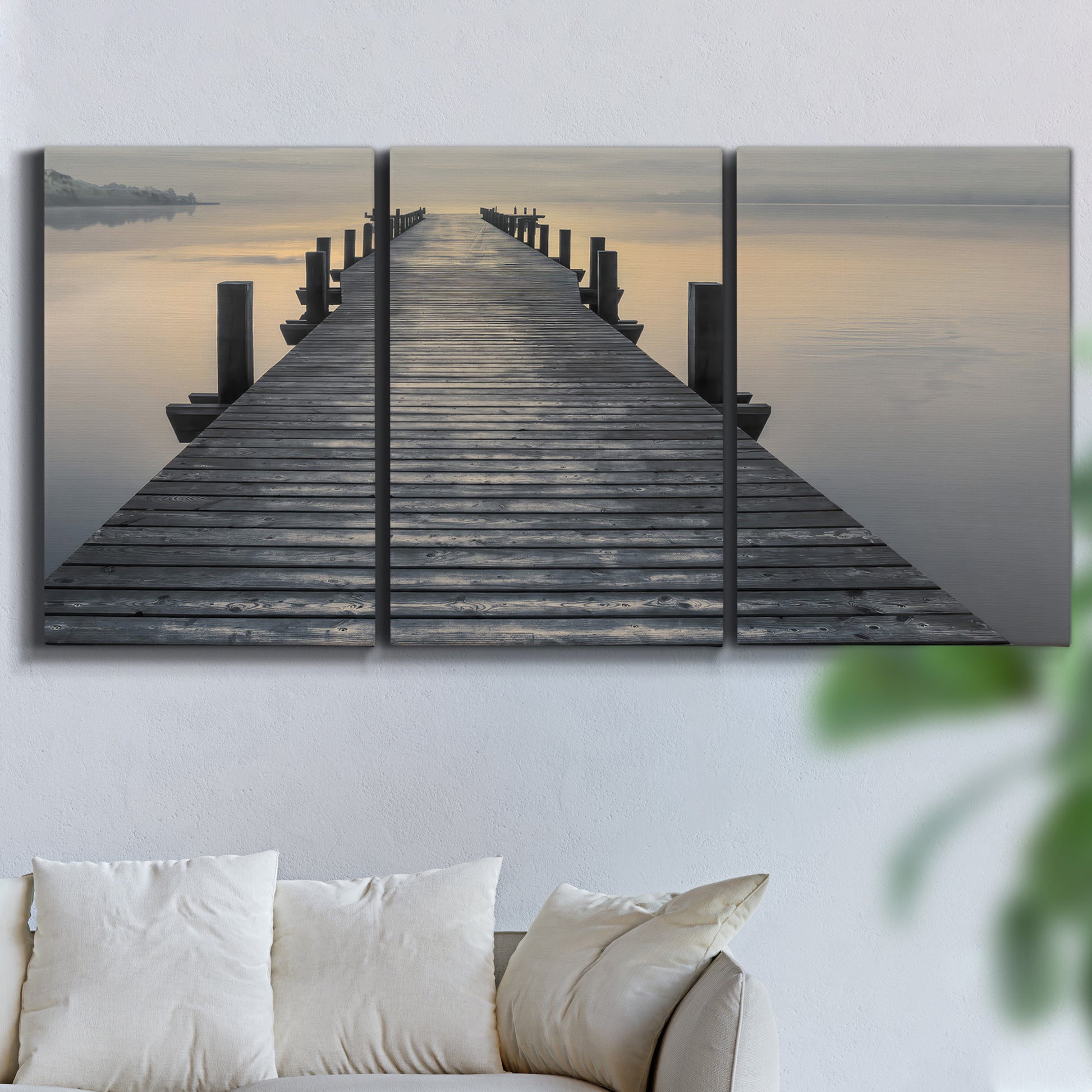 Three-panel canvas wall art featuring sunset over water photograph, displayed in a living room above a sofa.