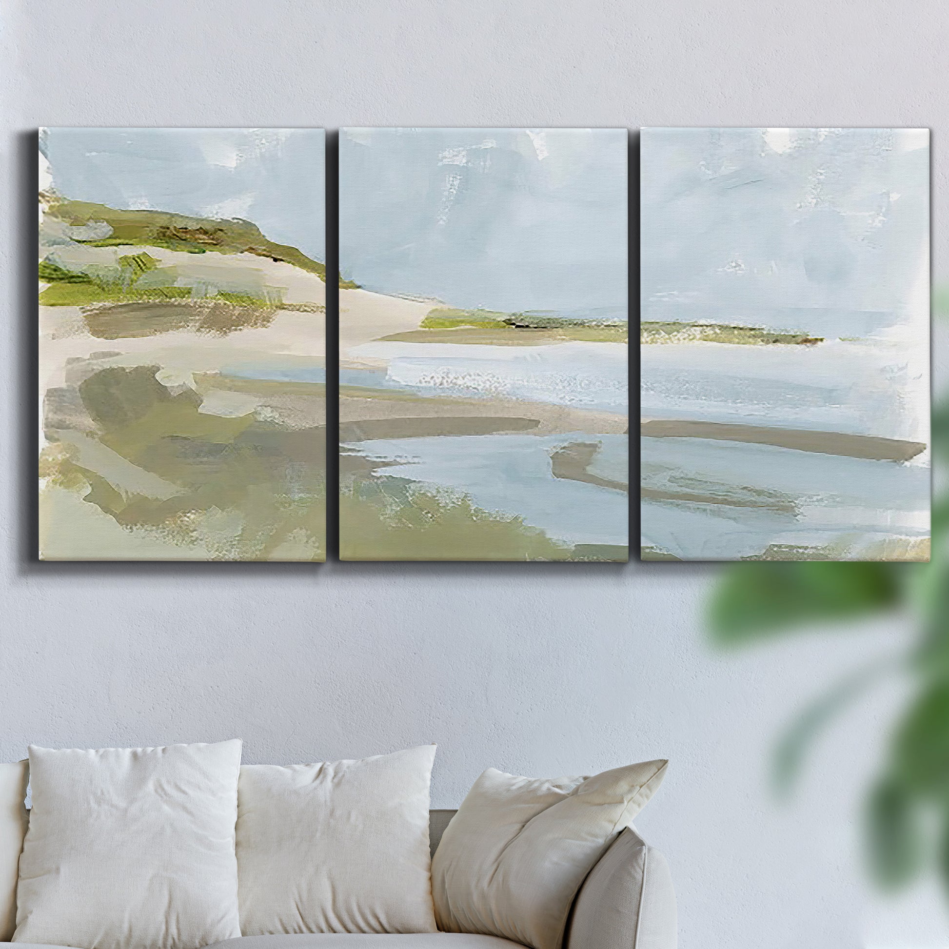 Three-panel canvas wall art featuring coastal cove with calm water, displayed in a living room above a sofa.