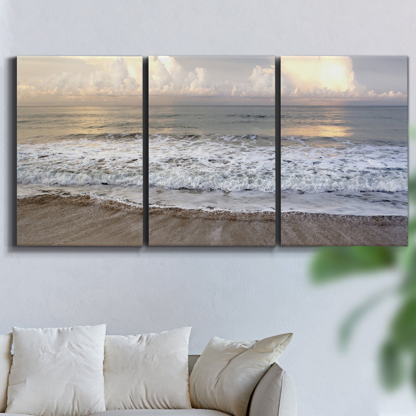 Three-panel canvas wall art featuring calm coastal shoreline seascape, displayed in a living room above a sofa.