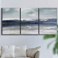 Three-panel canvas wall art featuring abstract coastal tones and movement, displayed in a living room above a sofa.
