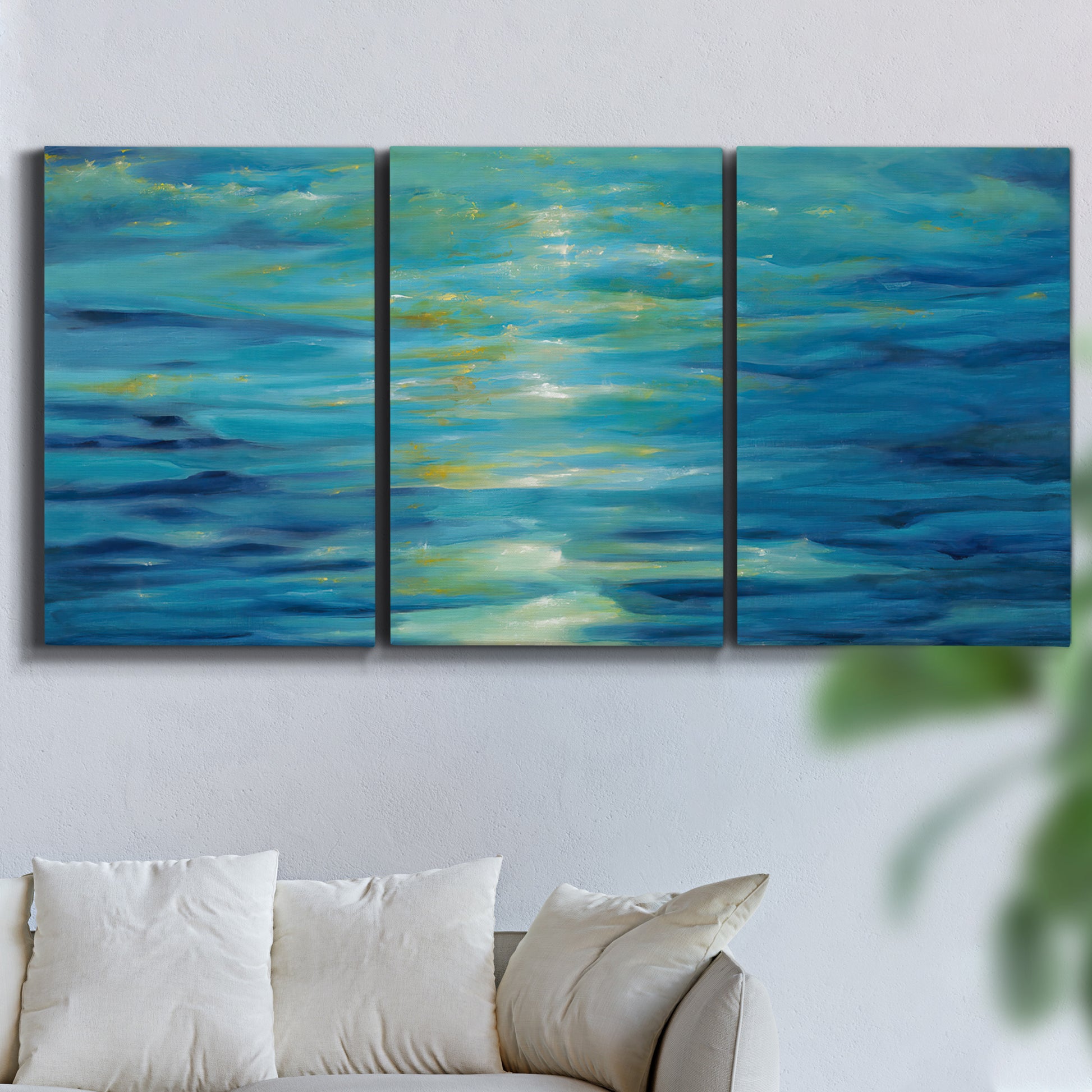 Three-panel canvas wall art featuring deep blue ocean water abstraction, displayed in a living room above a sofa.
