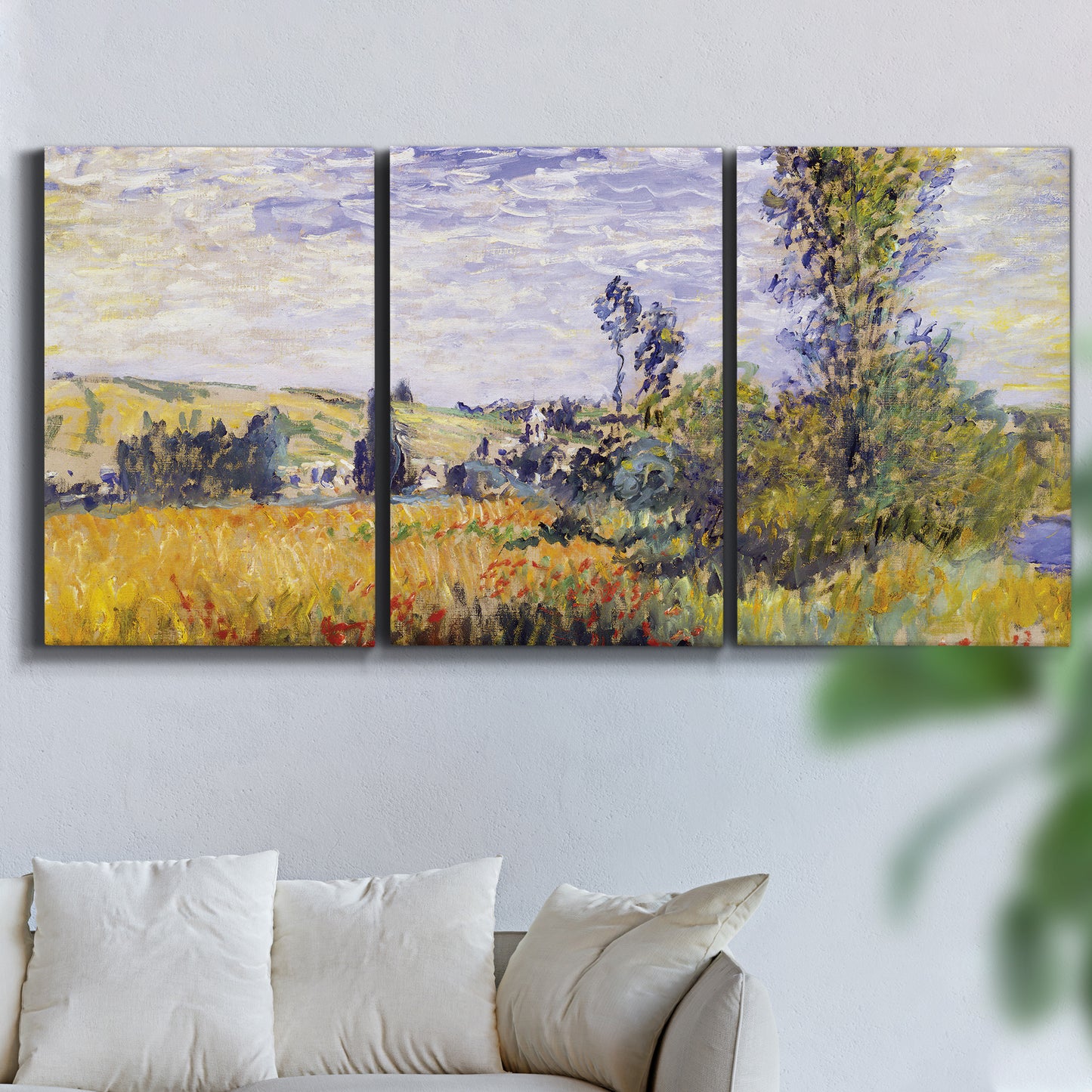 Three-panel canvas wall art featuring river village landscape with hills, displayed in a living room above a sofa.
