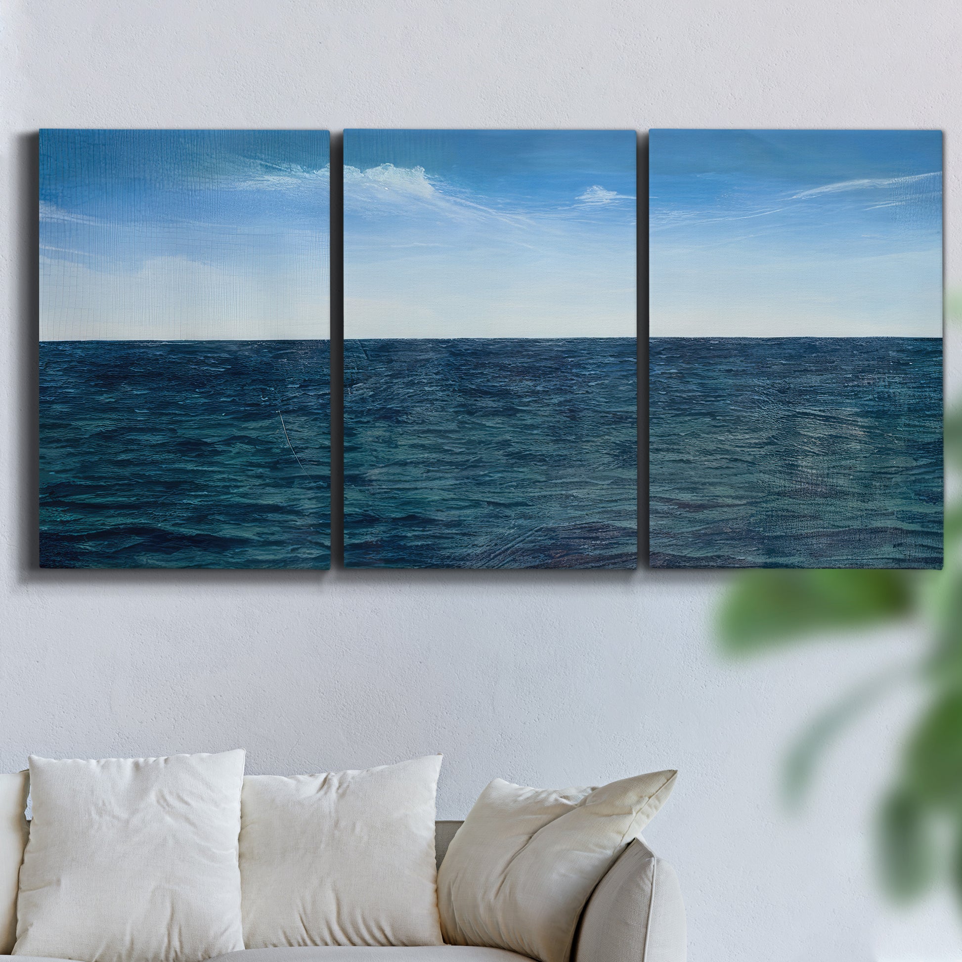 Three-panel canvas wall art featuring open water landscape with wide horizon, displayed in a living room above a sofa.