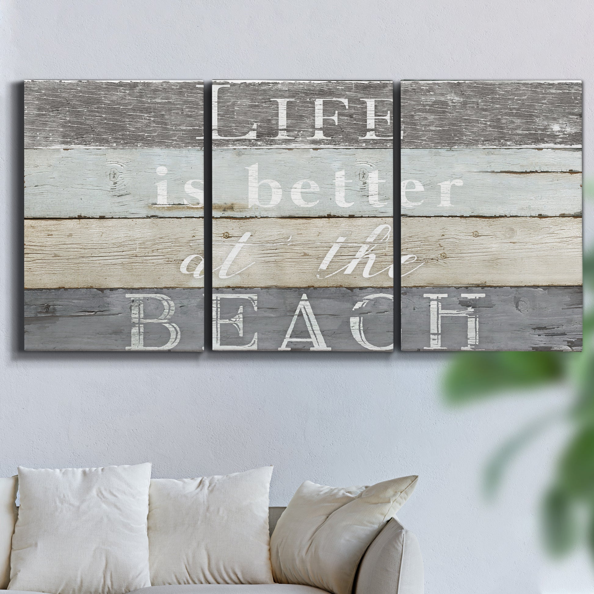 Three-panel canvas wall art featuring beach themed typography design, displayed in a living room above a sofa.