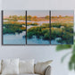 Three-panel canvas wall art featuring pastoral marshland landscape, displayed in a living room above a sofa.