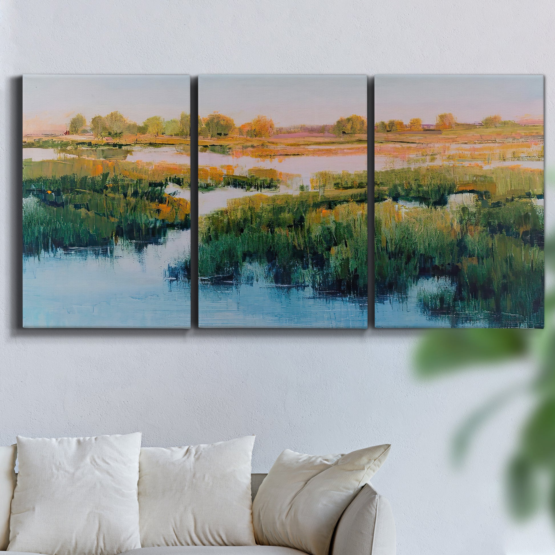 Three-panel canvas wall art featuring pastoral marshland landscape, displayed in a living room above a sofa.