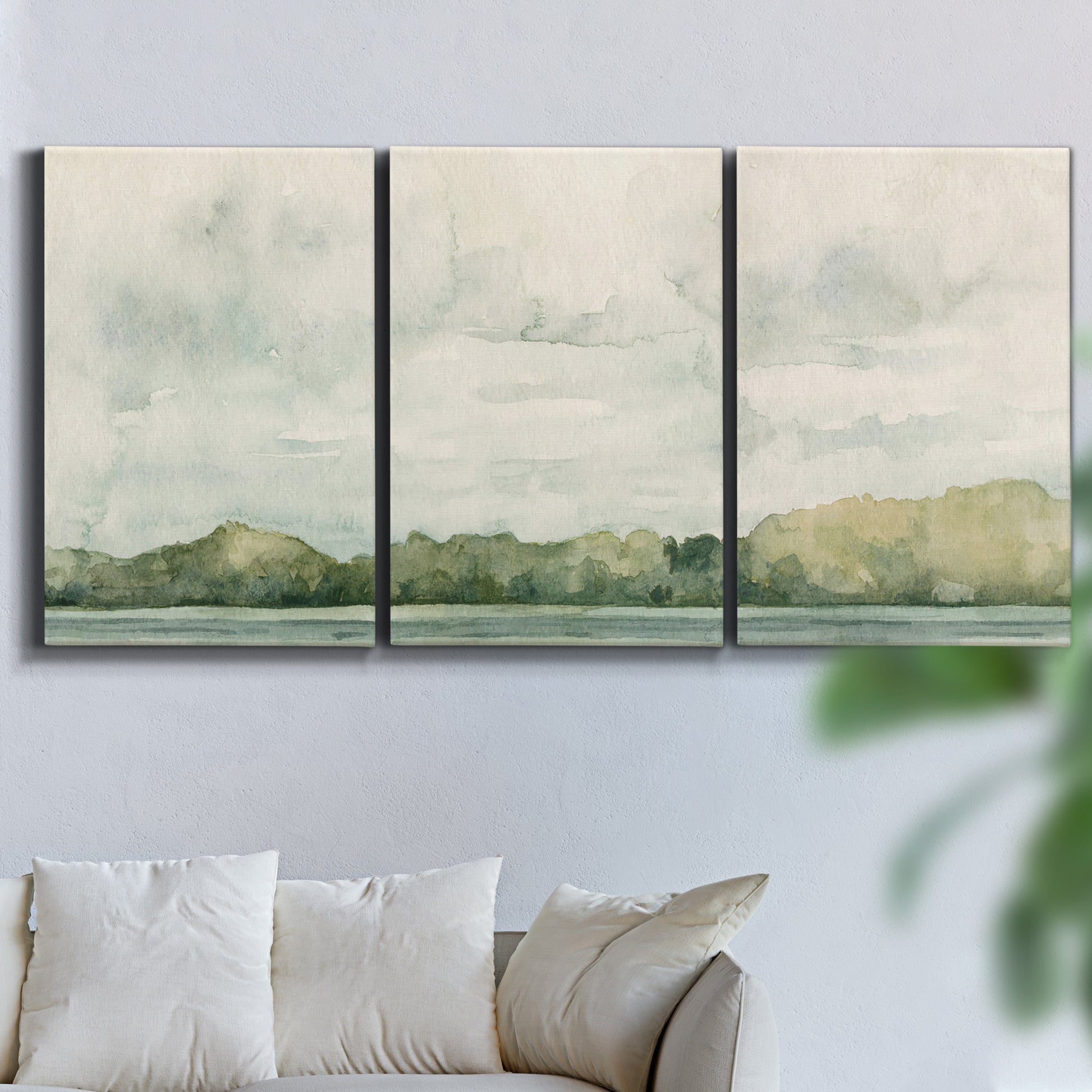 Three-panel canvas wall art featuring riverbank landscape with trees, displayed in a living room above a sofa.