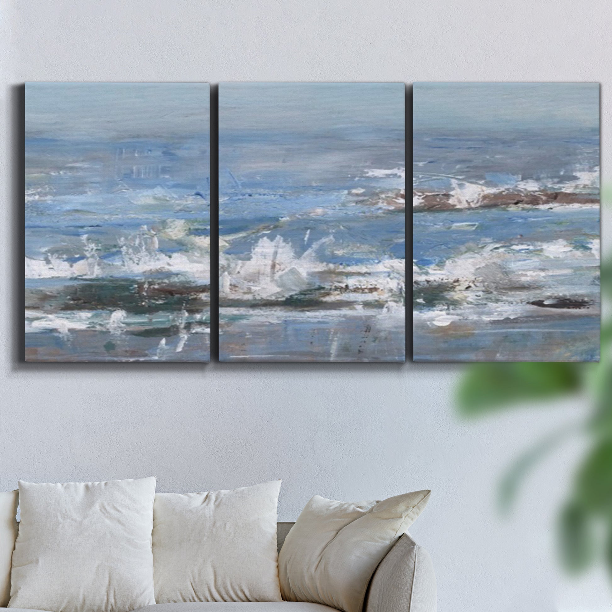 Three-panel canvas wall art featuring overcast coastal waves under grey sky, displayed in a living room above a sofa.