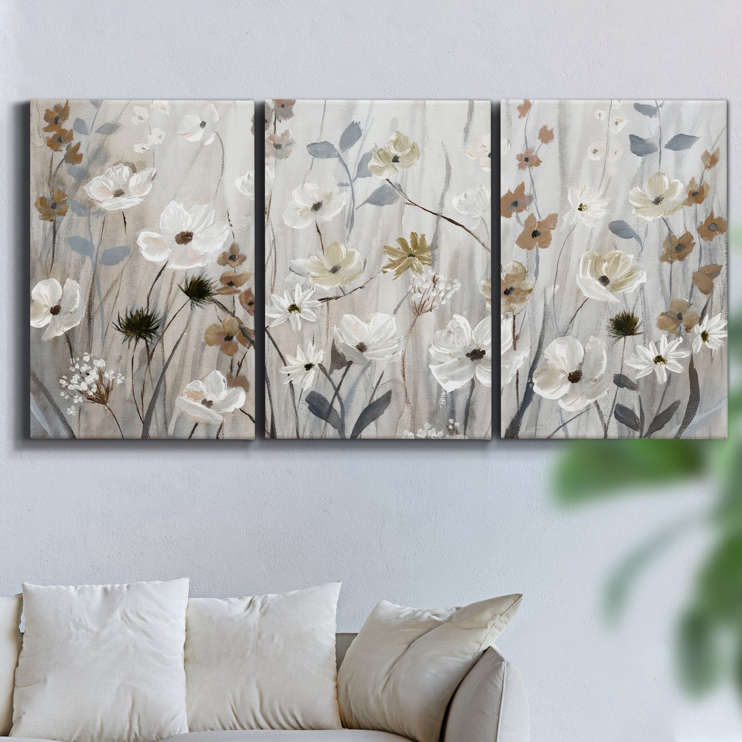Three-panel canvas wall art featuring misty wildflower meadow landscape, displayed in a living room above a sofa.