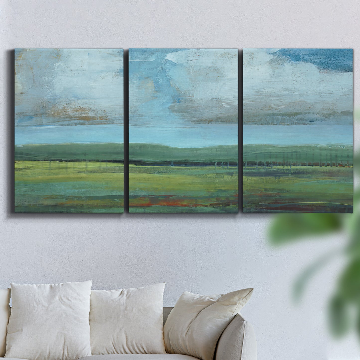 Three-panel canvas wall art featuring wide valley landscape with rolling hills, displayed in a living room above a sofa.