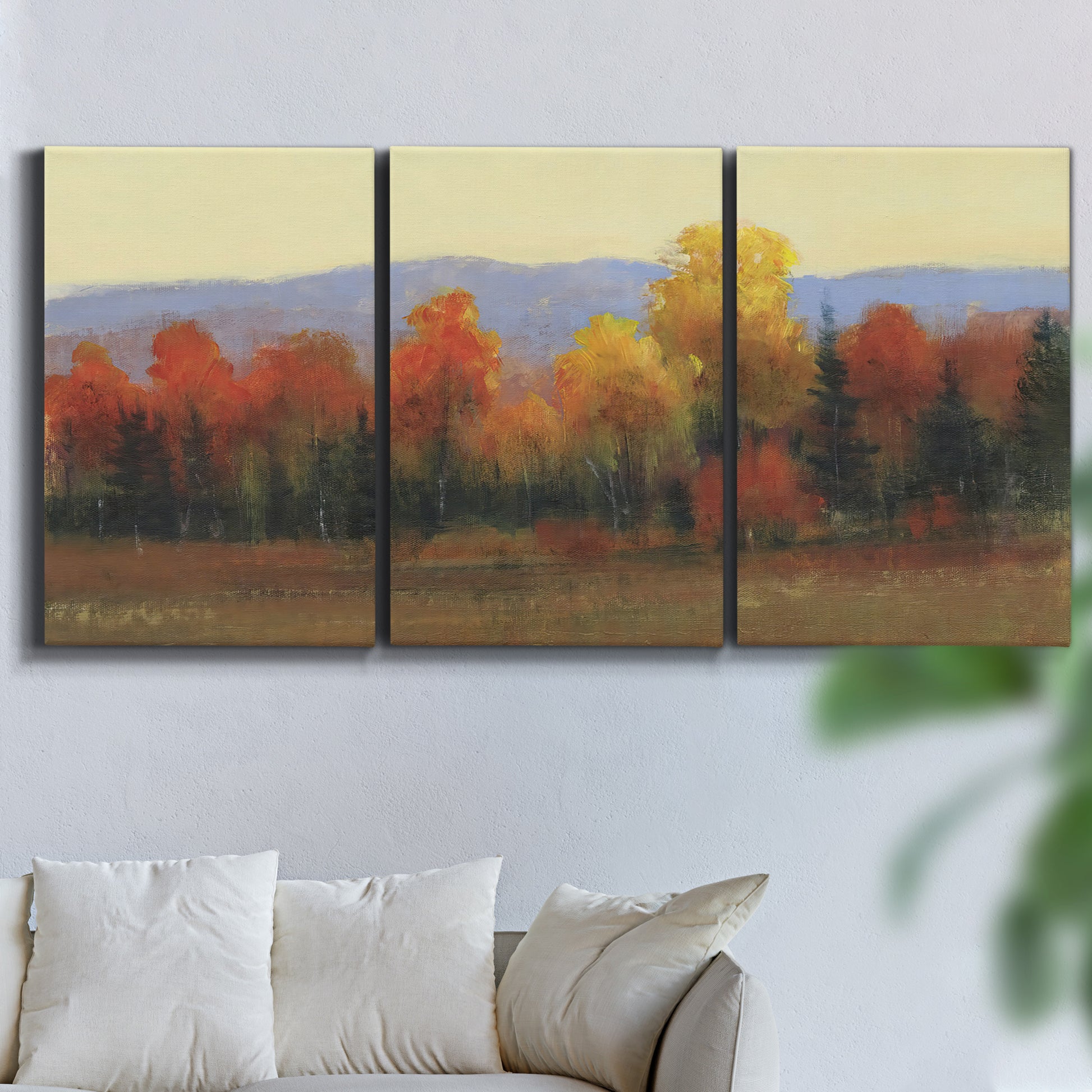 Three-panel canvas wall art featuring autumn landscape changing foliage, displayed in a living room above a sofa.