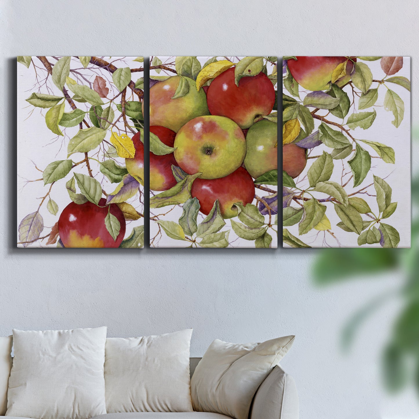 Three-panel canvas wall art featuring apples hanging from branch, displayed in a living room above a sofa.