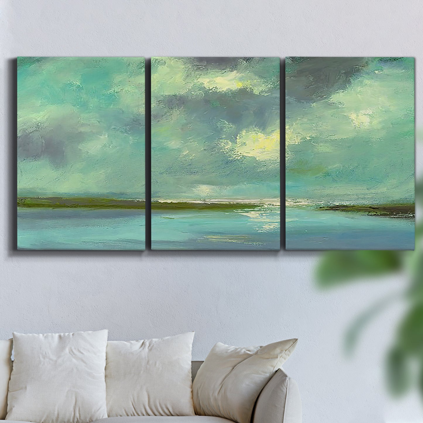 Three-panel canvas wall art featuring still lagoon water beneath open sky, displayed in a living room above a sofa.