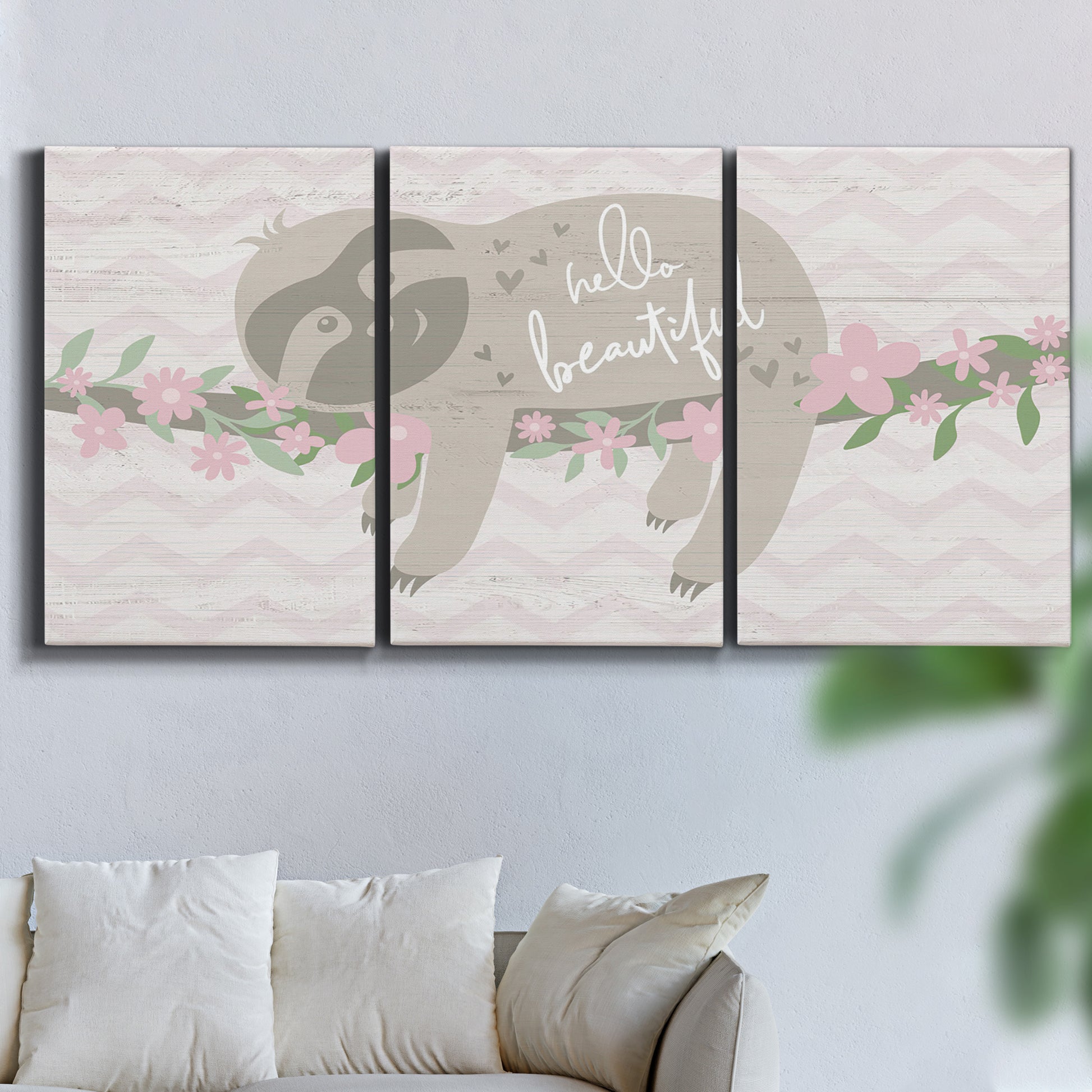 Three-panel canvas wall art featuring sloth with floral decorative elements, displayed in a living room above a sofa.