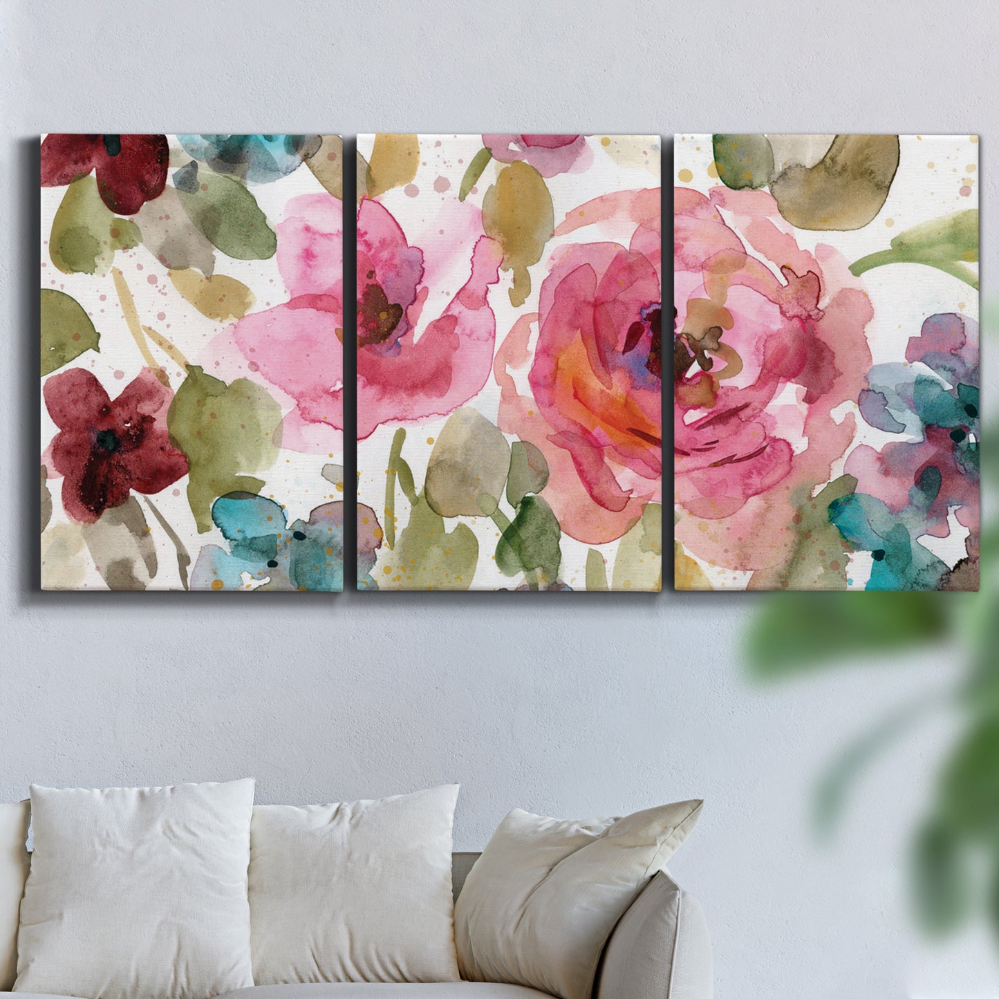 Three-panel canvas wall art featuring colorful floral watercolor composition, displayed in a living room above a sofa.