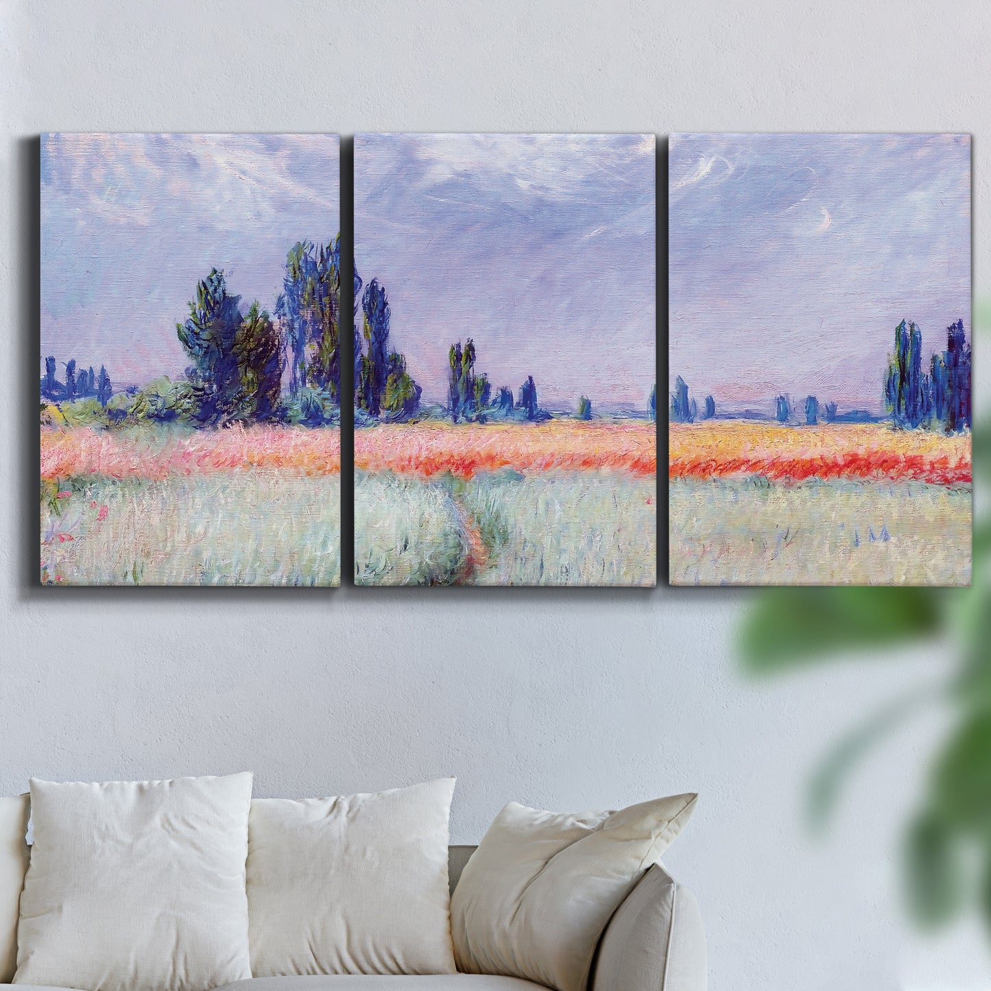 Three-panel canvas wall art featuring flowering field with poppies, displayed in a living room above a sofa.