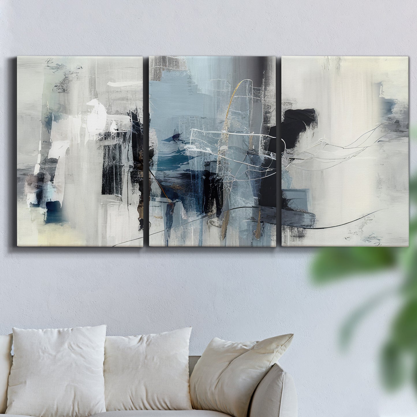 Three-panel canvas wall art featuring cool abstract winter color wash, displayed in a living room above a sofa.