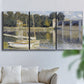 Three-panel canvas wall art featuring bridge crossing broad river, displayed in a living room above a sofa.