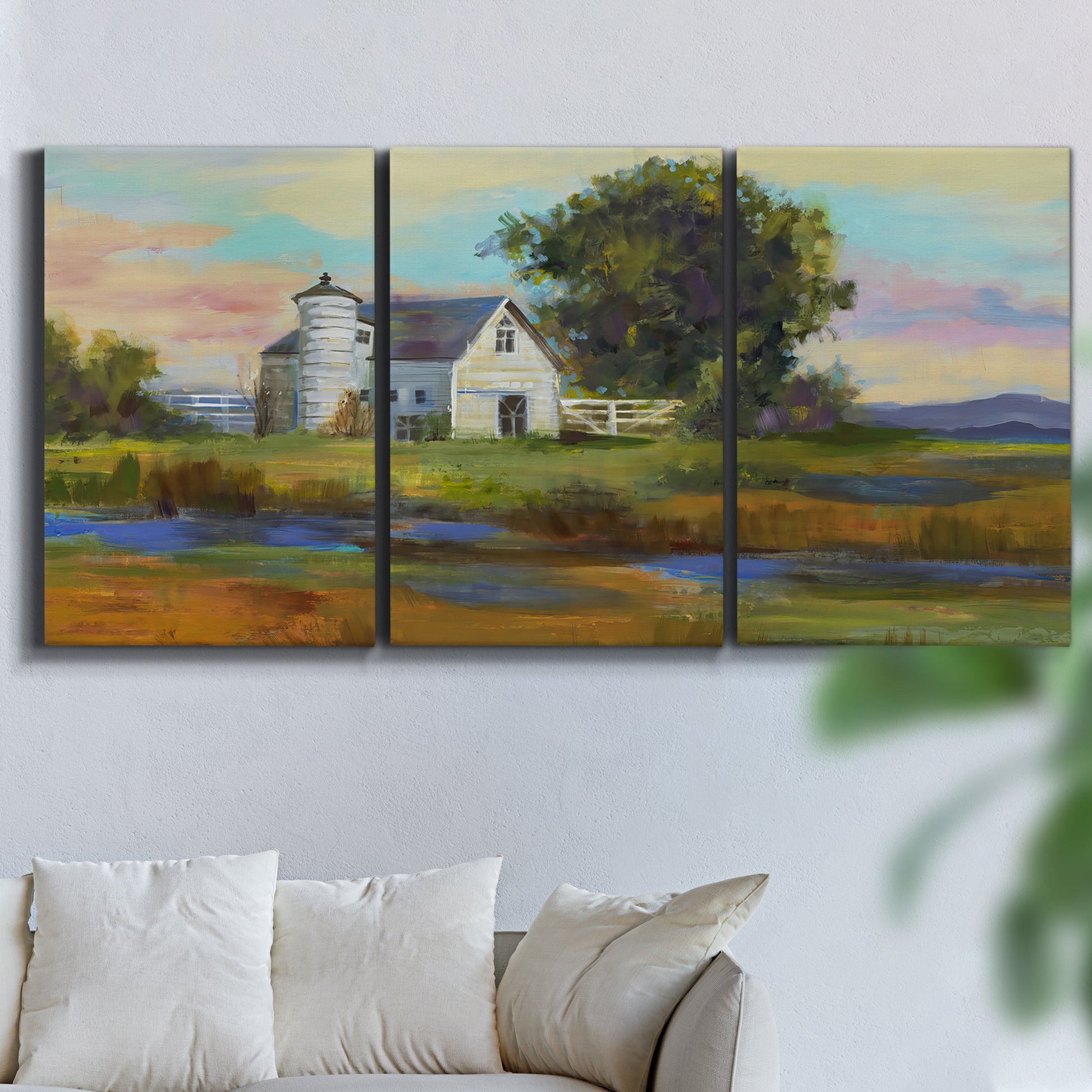 Three-panel canvas wall art featuring rural barn landscape with fields, displayed in a living room above a sofa.