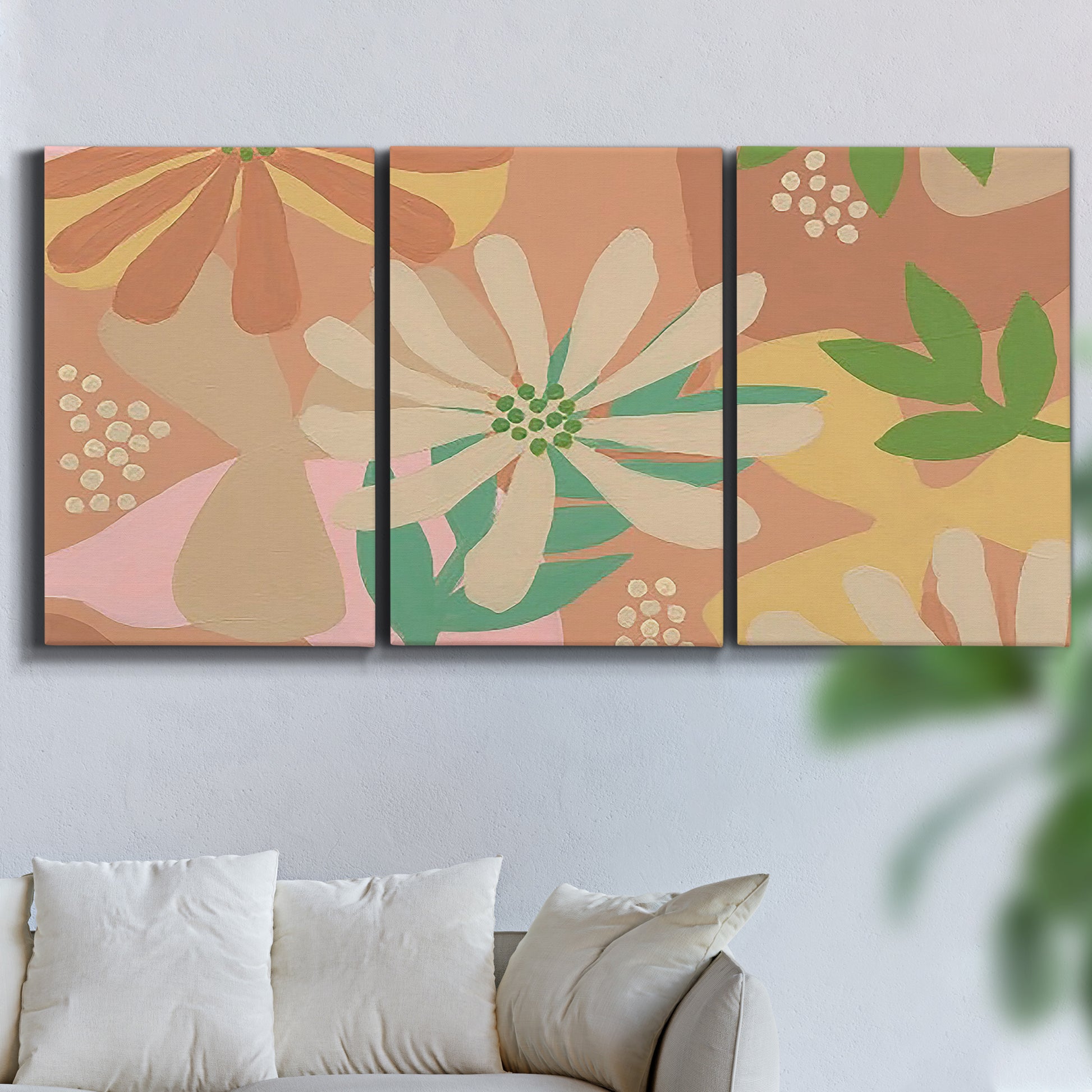 Three-panel canvas wall art featuring neutral toned botanical floral silhouettes, displayed in a living room above a sofa.