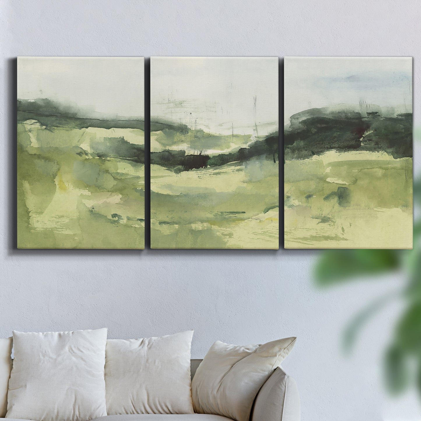 Three-panel canvas wall art featuring rolling hillside countryside landscape, displayed in a living room above a sofa.