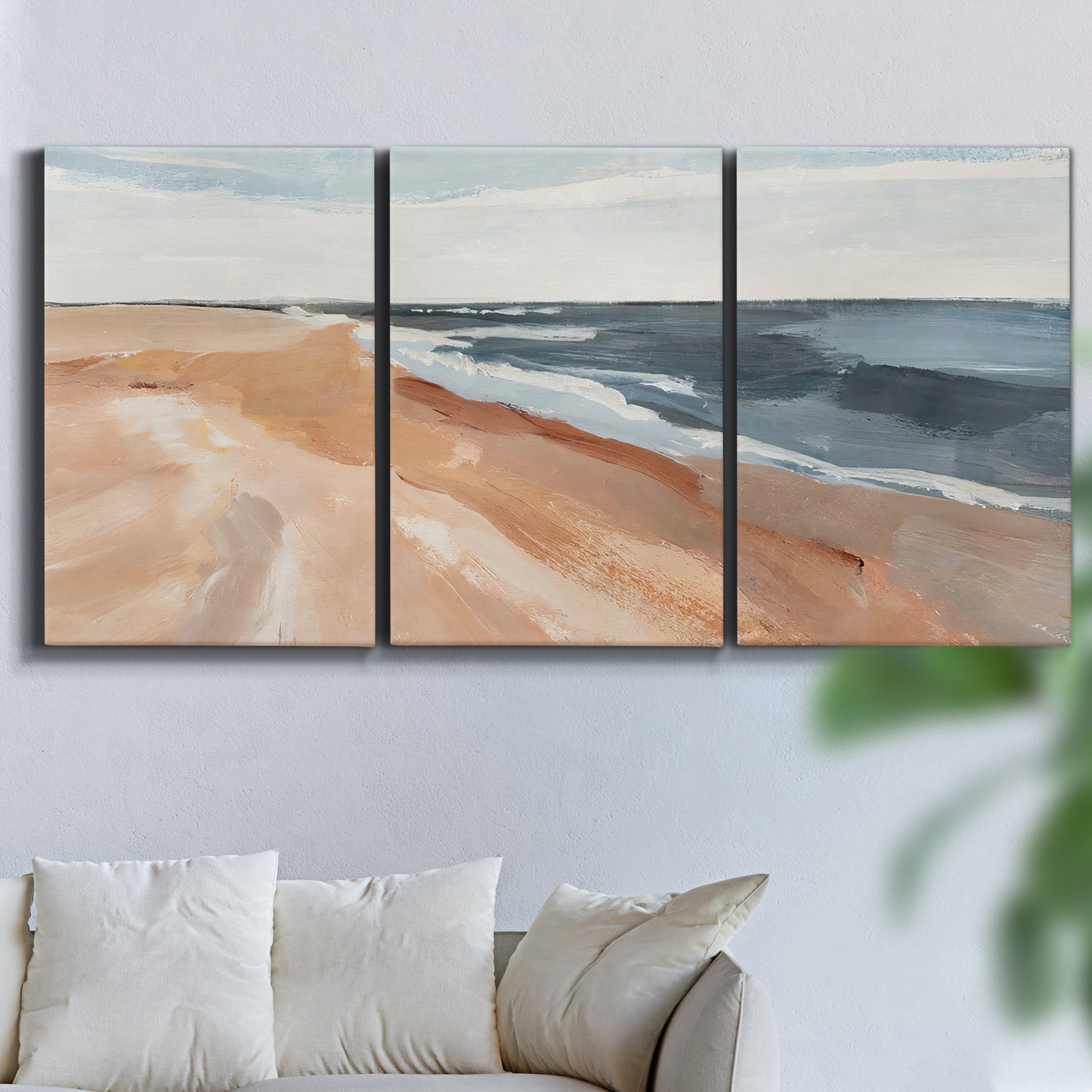 Three-panel canvas wall art featuring abstract coastal beach composition, displayed in a living room above a sofa.