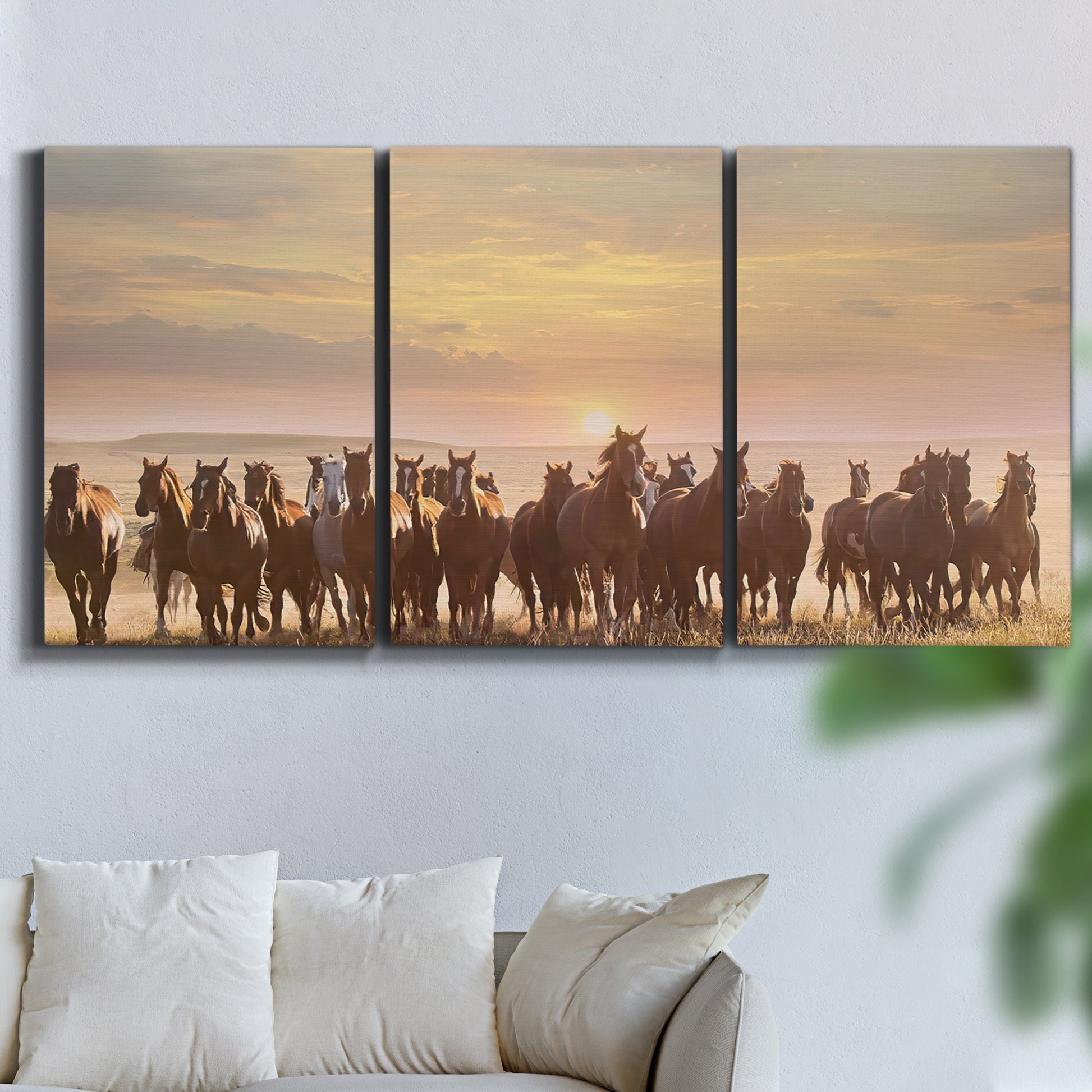Three-panel canvas wall art featuring running horses captured in motion, displayed in a living room above a sofa.