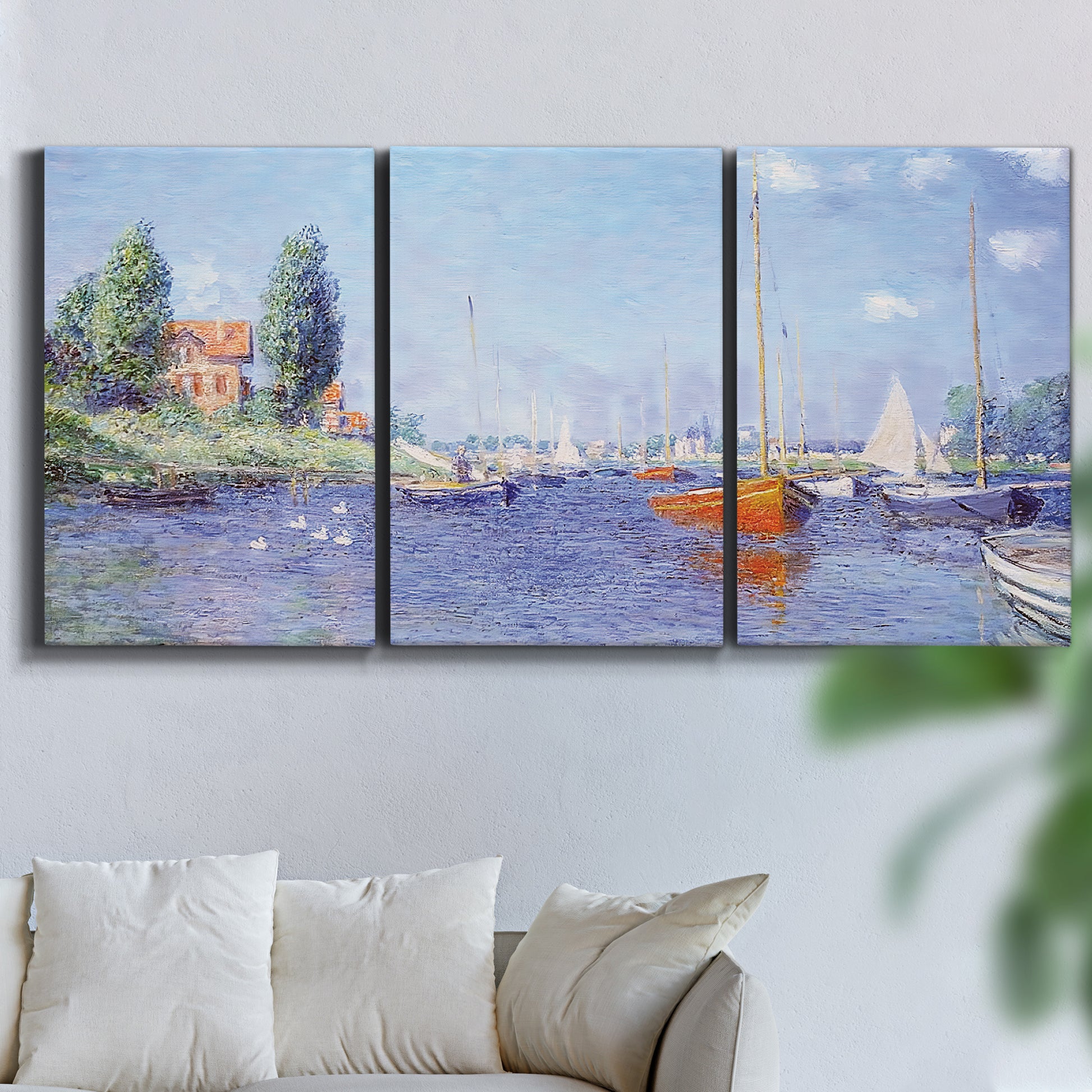 Three-panel canvas wall art featuring river flowing past riverside town, displayed in a living room above a sofa.