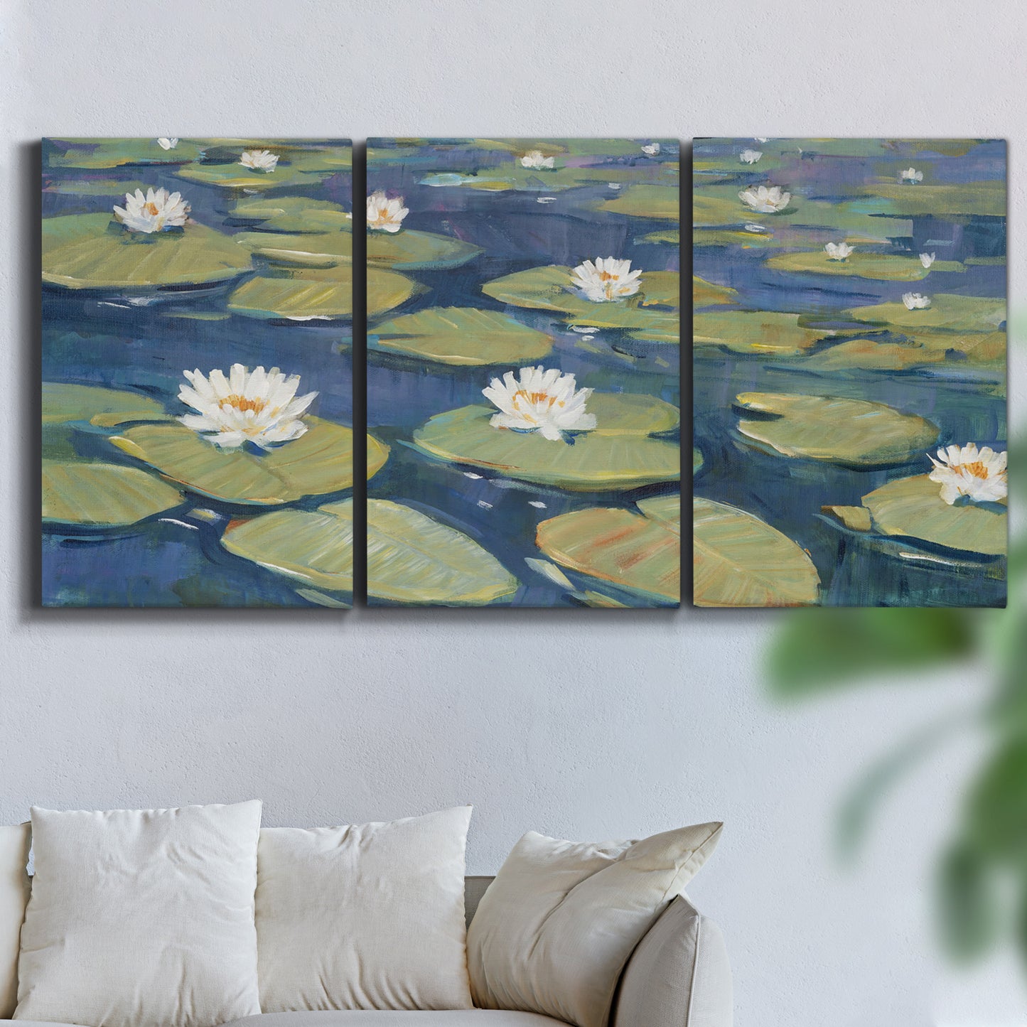 Three-panel canvas wall art featuring water lilies floating on pond, displayed in a living room above a sofa.