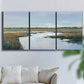 Three-panel canvas wall art featuring coastal plain meeting open water, displayed in a living room above a sofa.