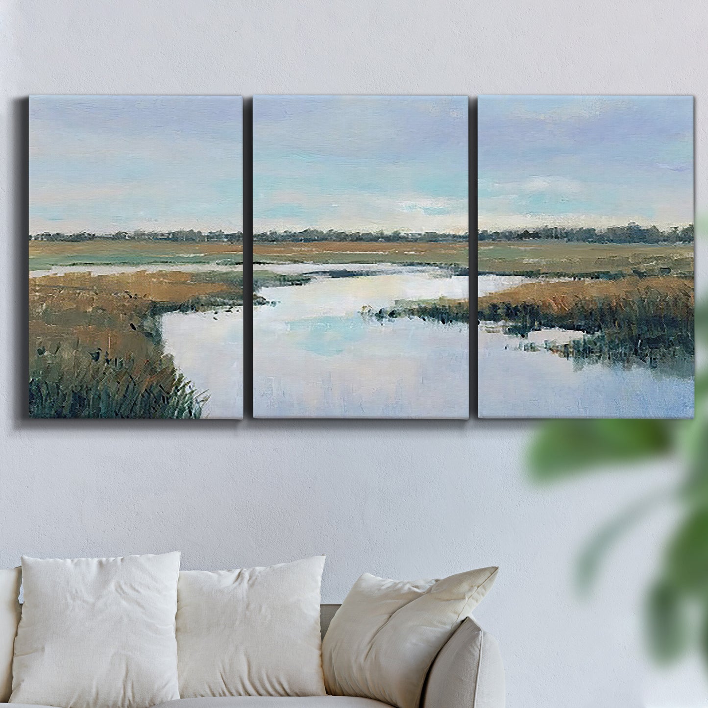 Three-panel canvas wall art featuring coastal plain meeting open water, displayed in a living room above a sofa.