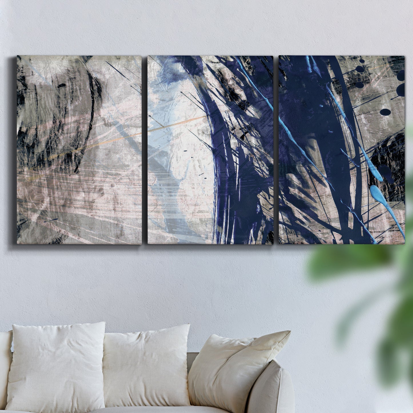 Three-panel canvas wall art featuring layered blue abstract texture, displayed in a living room above a sofa.