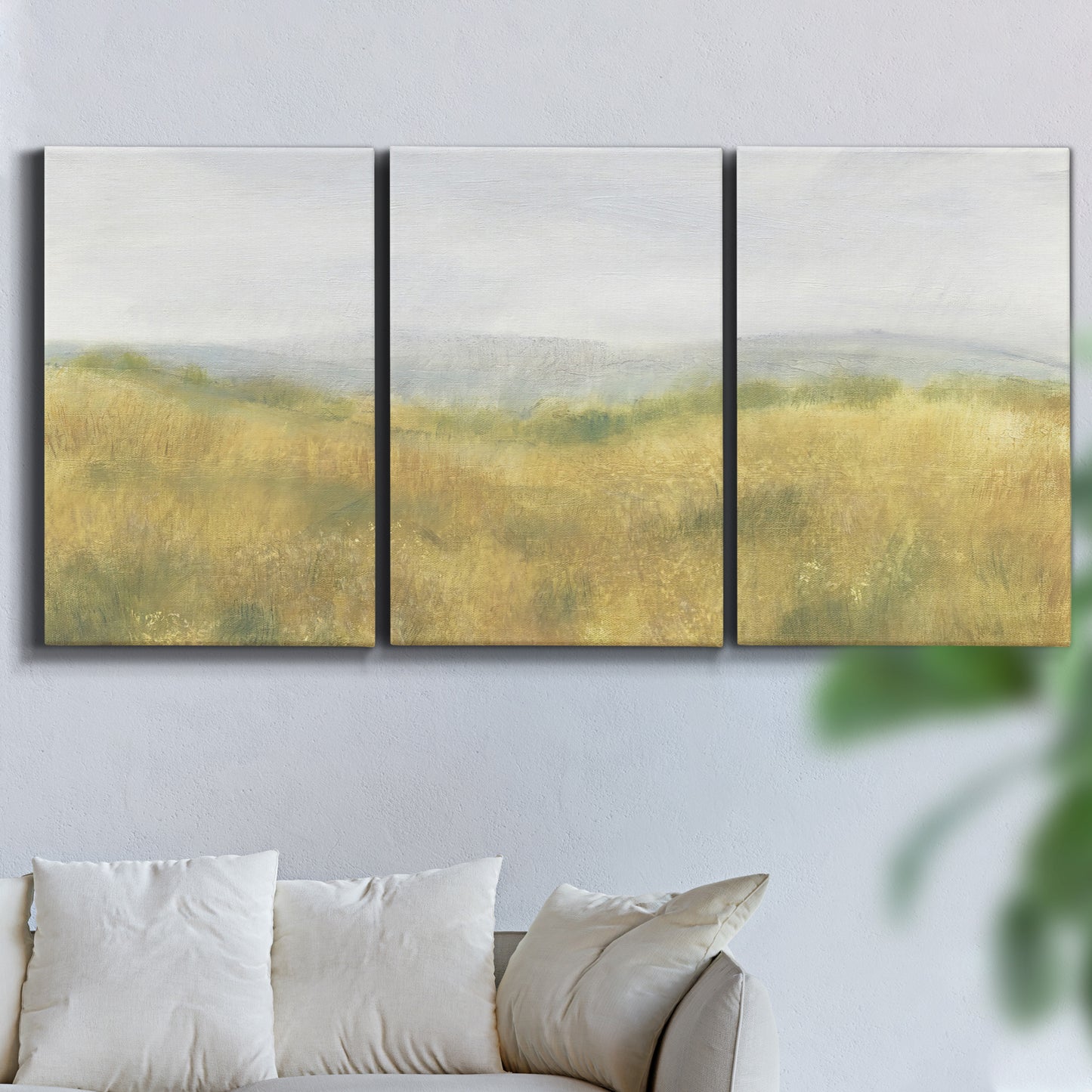 Three-panel canvas wall art featuring pastoral wheat field landscape, displayed in a living room above a sofa.