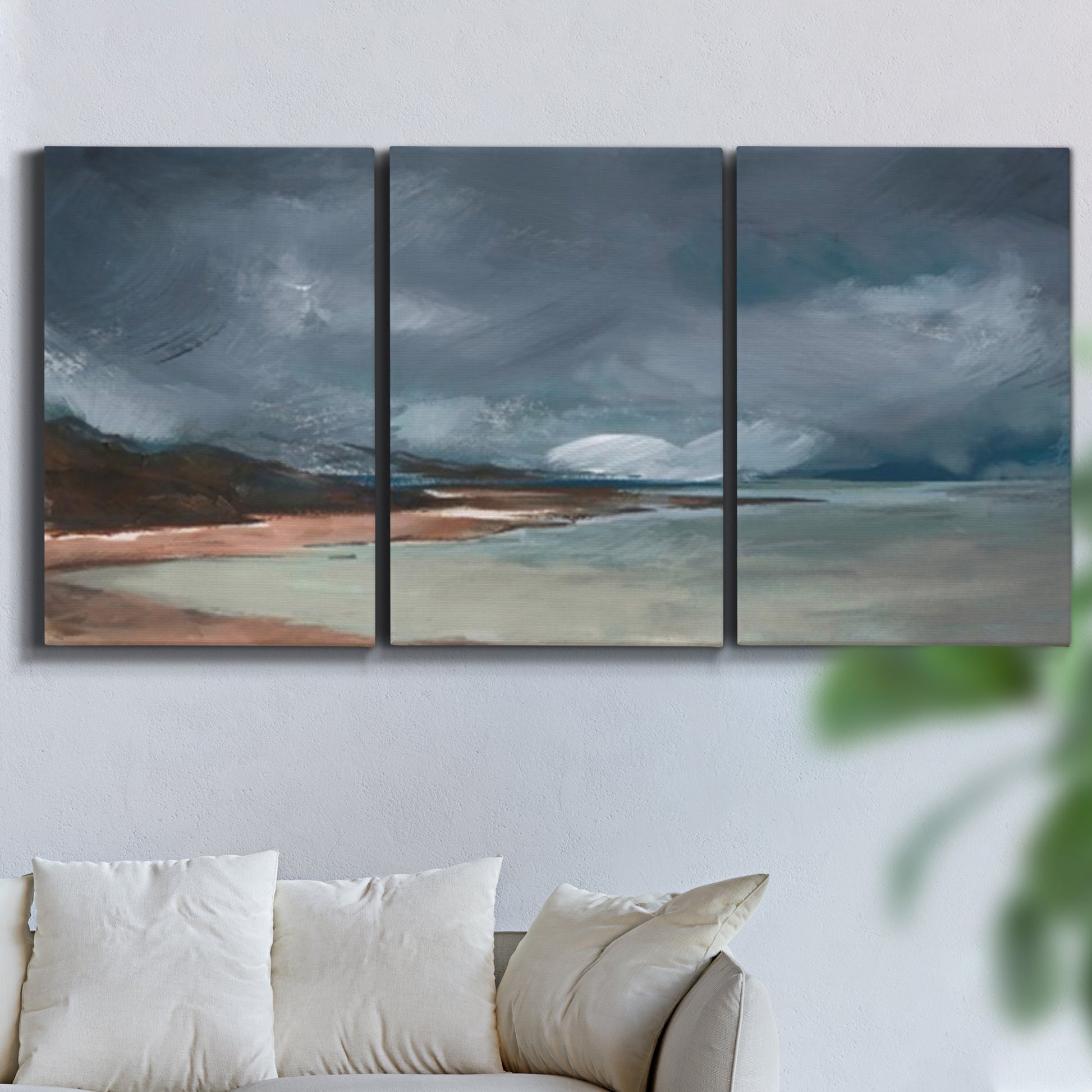 Three-panel canvas wall art featuring stormy sea glass toned coastline, displayed in a living room above a sofa.