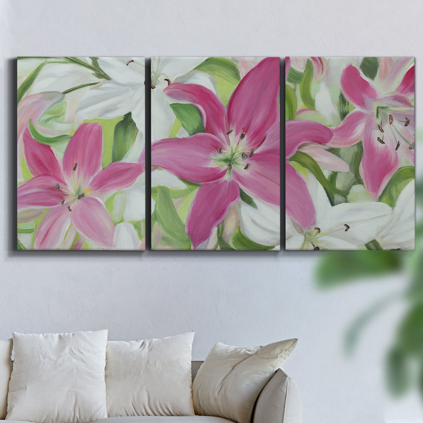 Three-panel canvas wall art featuring pink and white lilies in bloom, displayed in a living room above a sofa.