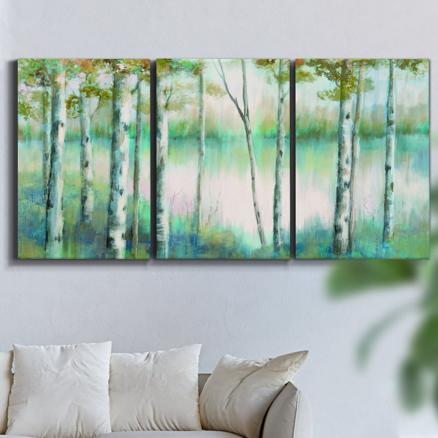 Three-panel canvas wall art featuring calm lake framed by aspen trees, displayed in a living room above a sofa.