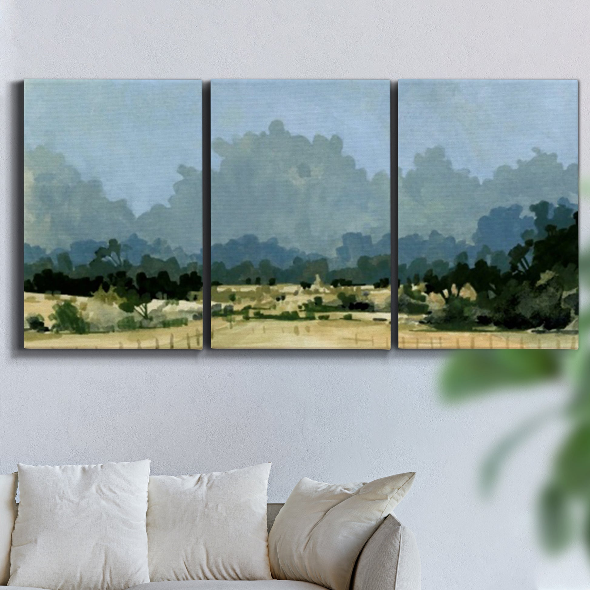 Three-panel canvas wall art featuring rural farmland landscape in watercolor, displayed in a living room above a sofa.