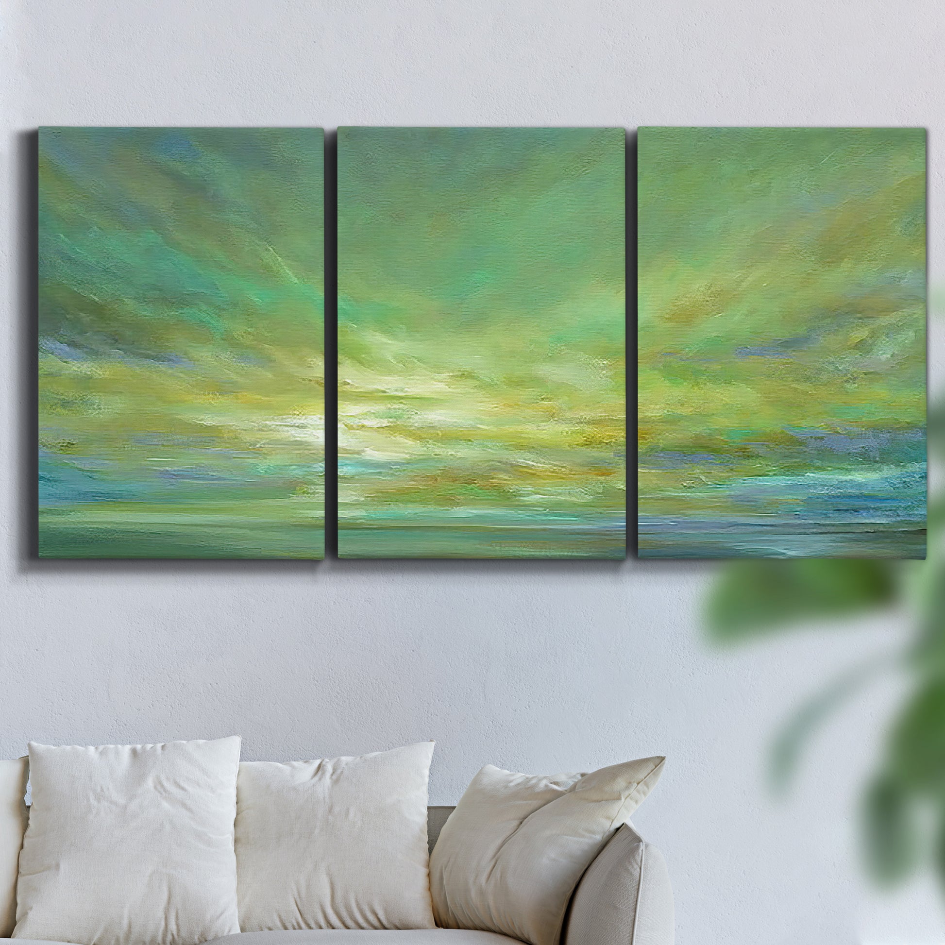 Three-panel canvas wall art featuring coastal shoreline under open sky, displayed in a living room above a sofa.