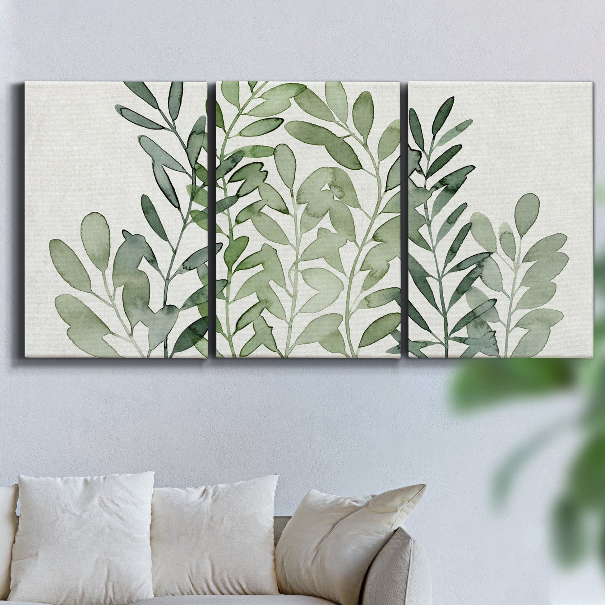Three-panel canvas wall art featuring foraged leafy greens botanical study, displayed in a living room above a sofa.