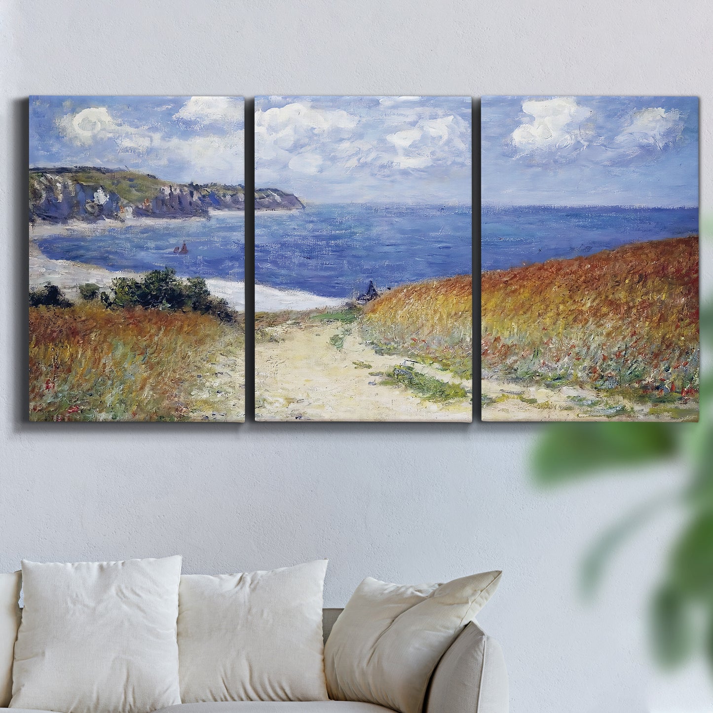 Three-panel canvas wall art featuring coastal path leading to sea, displayed in a living room above a sofa.