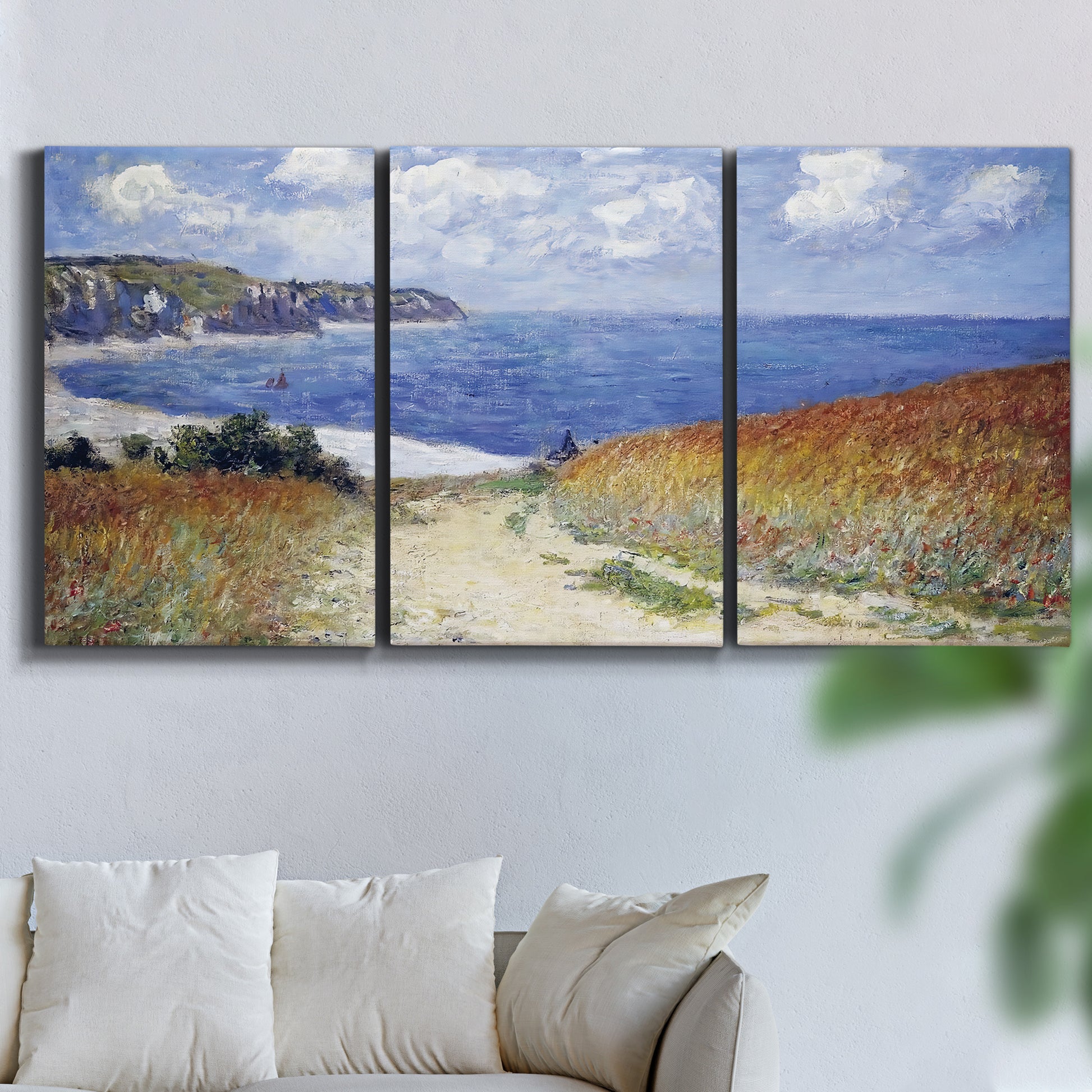 Three-panel canvas wall art featuring coastal path leading to sea, displayed in a living room above a sofa.